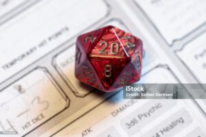 Focused shot of a red D20 die on a character sheet, highlighting critical game moments in tabletop role-playing games.